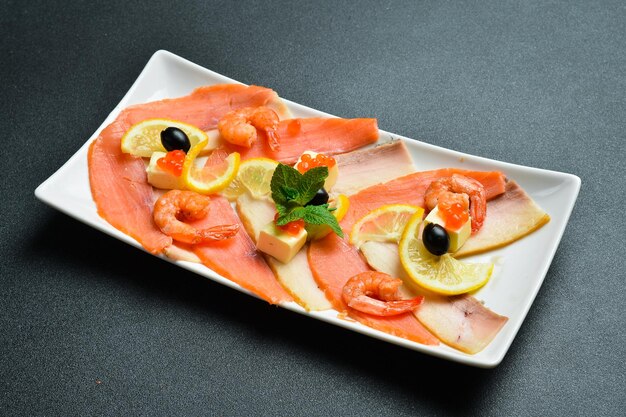 Salted salmon shrimp and caviar with butter and lemon Appetizer On a dark stone background Free space for text