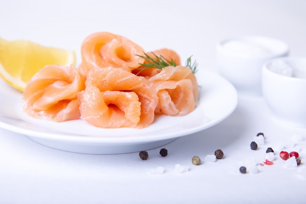 Salmone salato su un piatto bianco con limone e aneto. sfondo bianco, messa a fuoco selettiva, primo piano.