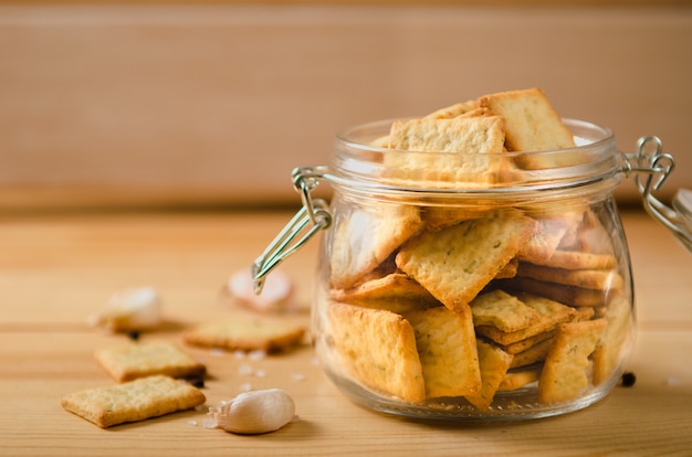 Salted snacks with pepper, salt, greens in glass jar on a wooden table