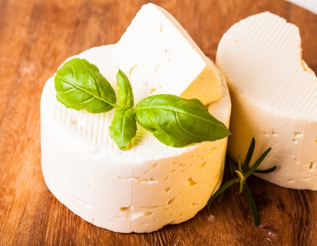 Salted soft cheese with basil leaf on the board