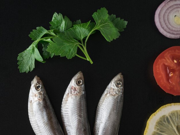 검은 테이블에 야채와 허브를 곁들인 소금에 절인 스프랫 맛있는 해산물 전채 플랫 레이