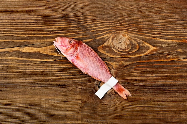 Salted sun-dried red mullet with label on tail on wooden table