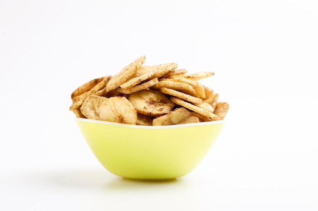 Salty banana chips in bowl on white background