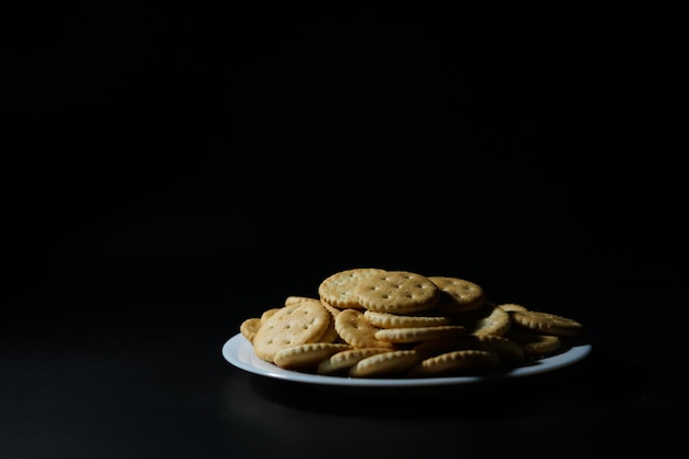 salty cookies, crackers, on a plate on a black background