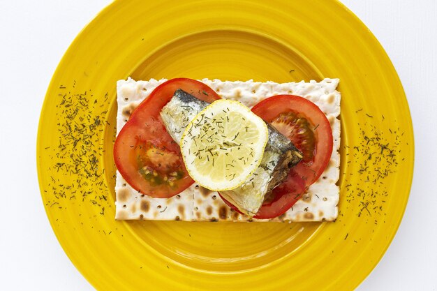 Salty crackers with sardine, tomato and lemon from above