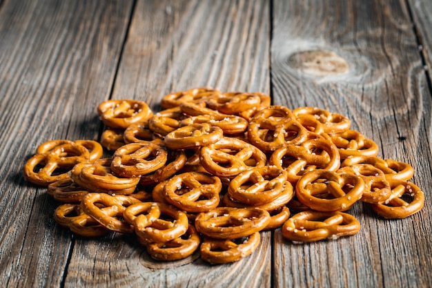 Salty mini party pretzels on a wooden surface closeup