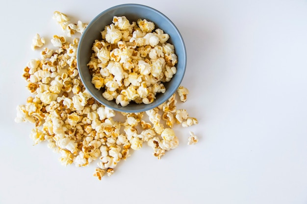 Salty popcorn in bowl on the white background, low angle view