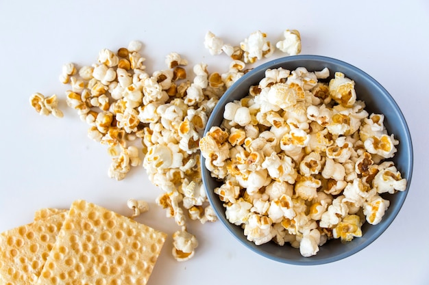 Salty popcorn in bowl on the white background, low angle view