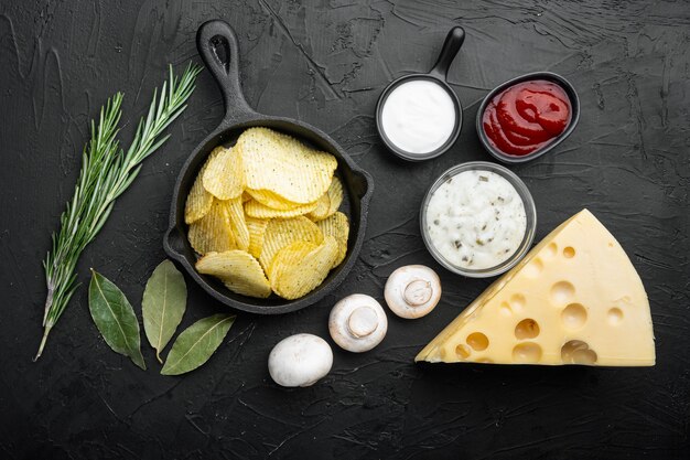 Salty potato chips snack set with Cheese and Onion, with sour cream, on black stone table, top view flat lay