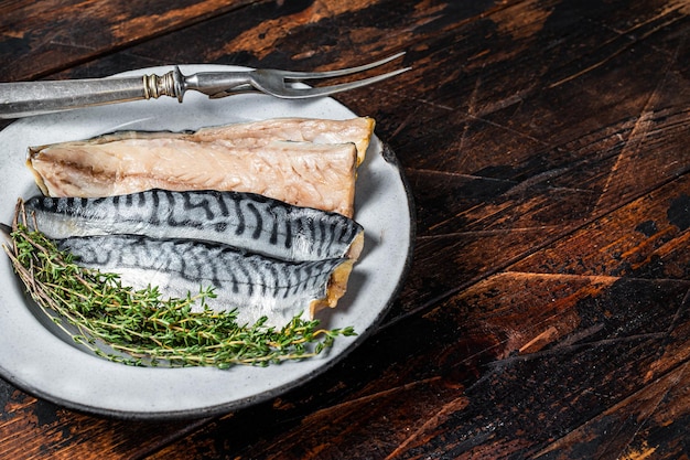 Filetto di sgombro affettato salato in un piatto con erbe sfondo in legno vista dall'alto spazio di copia