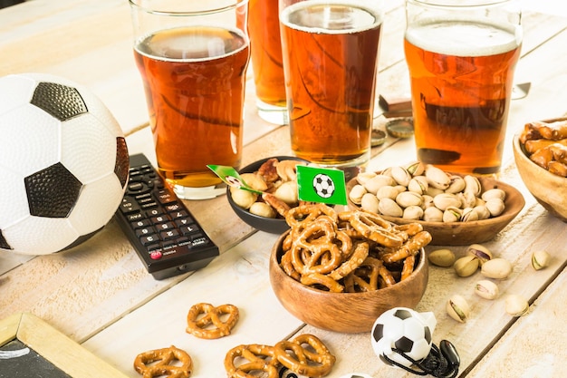 Salty snacks and beer on a table for soccer party.