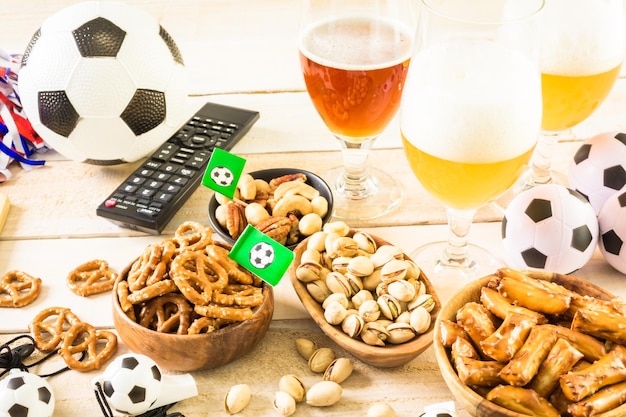 Salty snacks and beer on a table for soccer party.