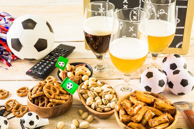 Salty snacks and beer on a table for soccer party.