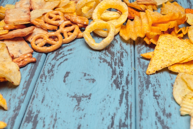 Snack salati. ciambelline salate, patatine fritte, cracker su fondo di legno. prodotti malsani