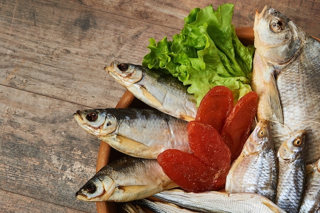 Salty stockfish on wooden table. Rainbow smelt, Common bream, Vobla, Shemay, Macrourus caviar and lettuce leaves.