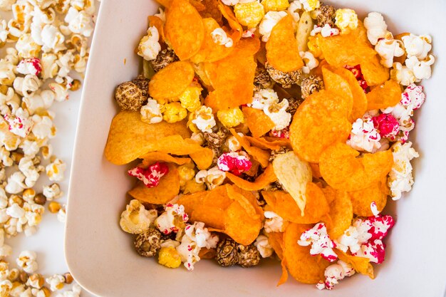 Salty and sweet popcorn and chips on the white background, low angle view