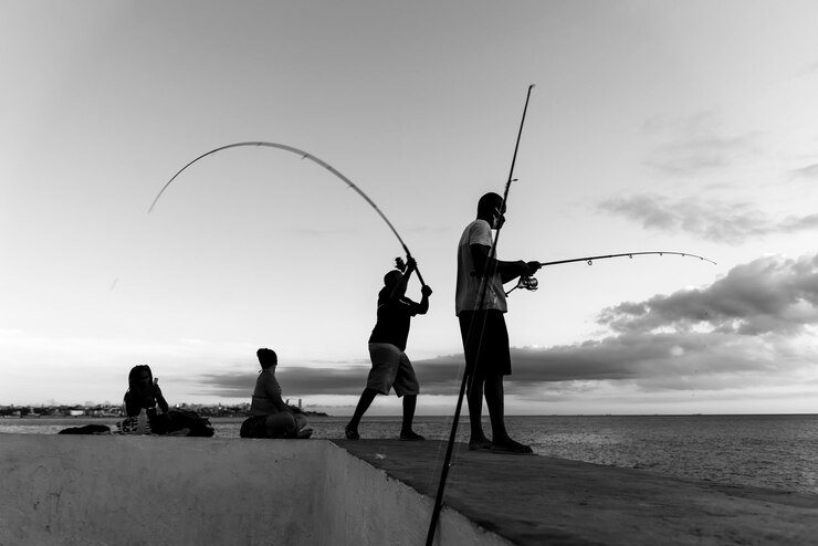 Photo サルバドール・バイーア州ブラジル 2021 年 5 月 23 日 魚を求めて岩の上に釣り竿を持つ漁師のシルエット