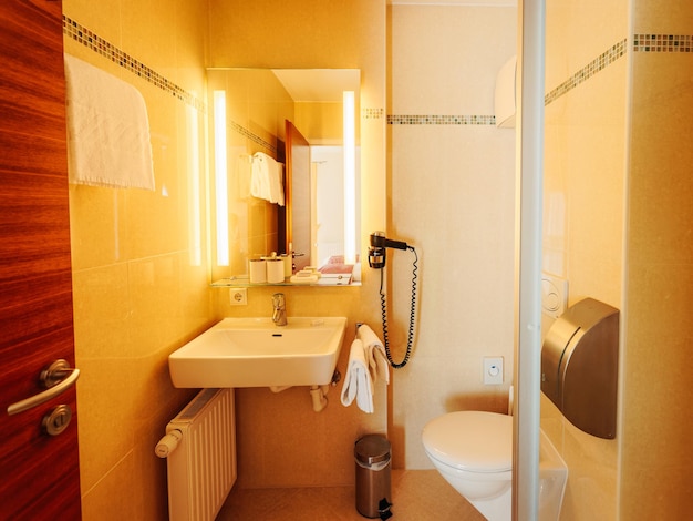 Photo salzburg, austria - february, 2019: interior of modern bathroom with wood design. home with mirror, sink, toilet bowl and shower. hotel bath room. house with toilet furniture and decor.