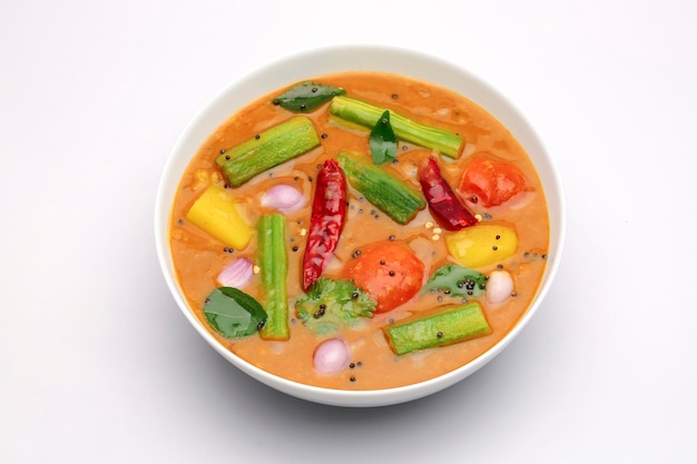 Sambar, mixed vegeterian curry arranged in a white bowl on a white textured background.