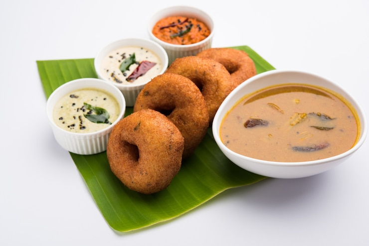 फोटो सांबर वड़ा या मेदू वड़ा, एक लोकप्रिय दक्षिण भारतीय भोजन जिसे मूडी बैकग्राउंड पर हरी, लाल और नारियल की चटनी के साथ परोसा जाता है। चयनात्मक ध्यान केंद्रित।