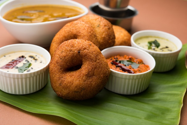 サンバーヴァーダまたはメドゥヴァーダ、不機嫌そうな背景の上に緑、赤、ココナッツのチャツネを添えた人気の南インド料理。セレクティブフォーカス
