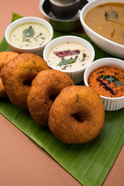Sambar vada of medu vada, een populair zuid-indiaas gerecht geserveerd met groene, rode en kokoschutney op een humeurige achtergrond. selectieve focus