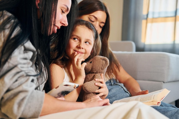 Samen boek lezen Vrouwelijk lesbisch koppel met kleine dochter die tijd samen thuis doorbrengt