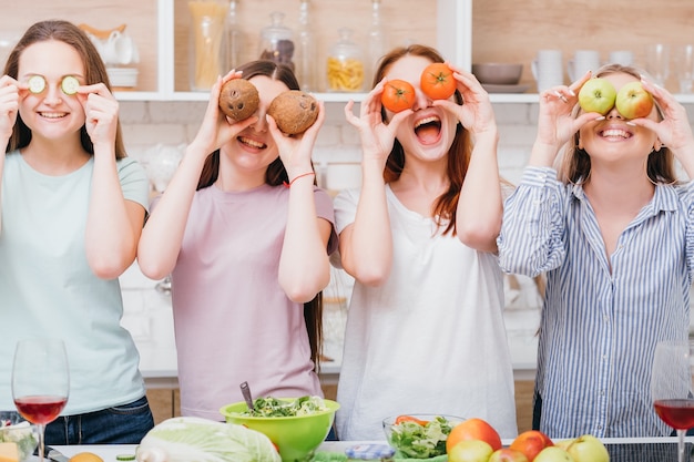 Samen diëten. Gezonde voeding. Biologisch koken. Opgewonden jonge vrouwtjes poseren met voedsel dat de ogen bedekt.