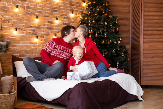 Samen genieten op vakantie. Gelukkige moeder, vader en klein kind hebben plezier in de buurt van de kerstboom thuis