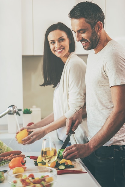 Samen koken is leuk. Mooie jonge verliefde paar samen koken terwijl je in de keuken staat