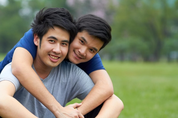 Samen leven en liefhebben Schattig jong homoseksueel Aziatisch stel dat samen lacht terwijl ze in het park zitten