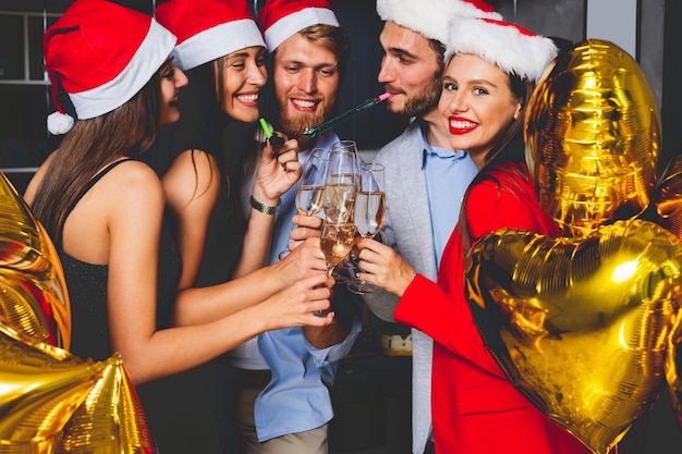 Samen nieuwjaar vieren. Groep mooie jonge mensen in Santa hoeden kleurrijke confetti gooien en op zoek gelukkig