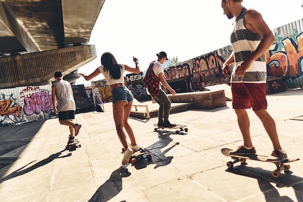 Samen onbezorgd genieten. Groep jonge moderne mensen die samen buiten skateboarden