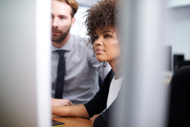 Samen oplossingen vinden Shot van een jonge vrouw en haar collega die achter een computer werken