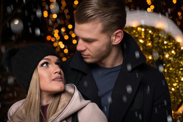 Samen plezier maken bij een kerstfee Jong vrolijk stel is aan het wandelen Genieten van warm gekleed kijken naar elkaar en lachen