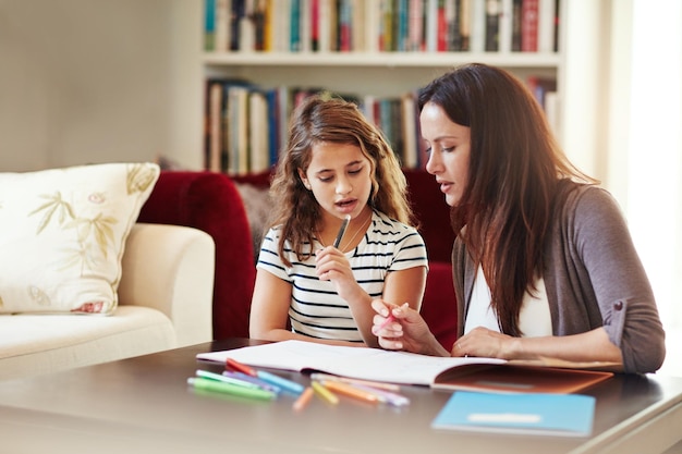 Samen proberen er achter te komen Shot van een mooie moeder die haar schattige dochter thuis helpt met haar huiswerk