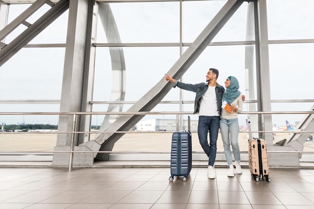 Samen reizen gelukkige moslim echtgenoten staan met koffers op de luchthaven