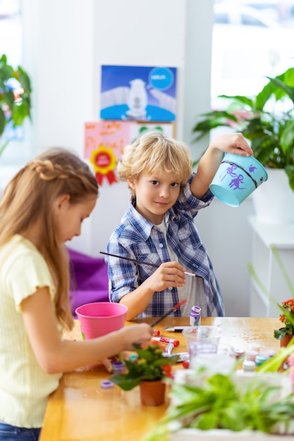 Samen schilderen. Jongen en meisje voelen zich goed tijdens het schilderen op bloempotten bij de les ecologie