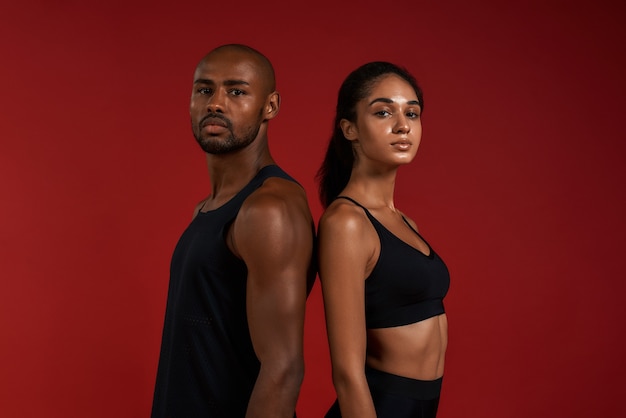 Samen werken aan een jong en zelfverzekerd Afrikaans fitnesspaar in sportkleding dat naar de camera kijkt