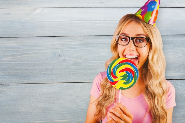 Samengesteld beeld van een mooie hipster die een gigantische lolly vasthoudt