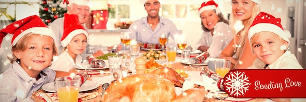 Samengesteld beeld van gelukkige familie die kerstmutsen draagt rond de eettafel