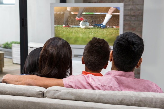 Samengesteld beeld van gelukkige familie die tv kijkt op de bank