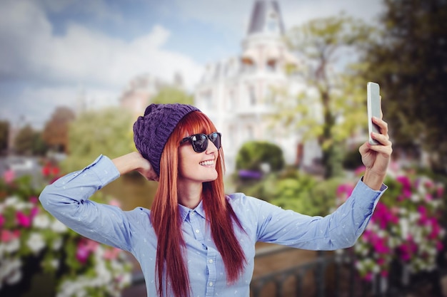 Samengesteld beeld van glimlachende hipstervrouw die selfie neemt