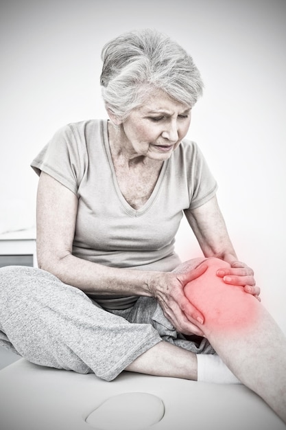 Samengesteld beeld van hogere vrouw met haar handen op een pijnlijke knie