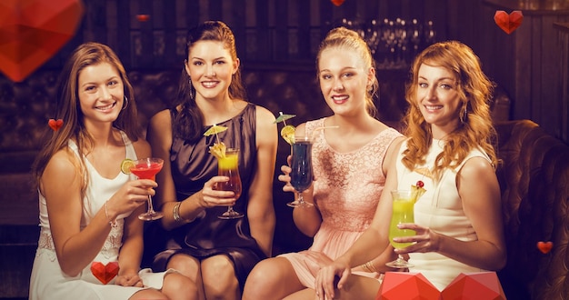 Foto samengesteld beeld van portret van vrouwelijke vrienden die glazen cocktail in bar houden