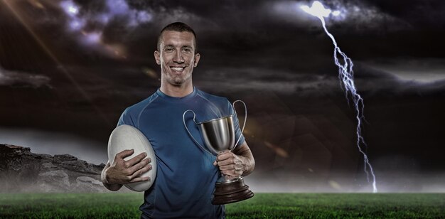 Samengestelde afbeelding 3D van portret van lachende rugbyspeler met trofee en bal