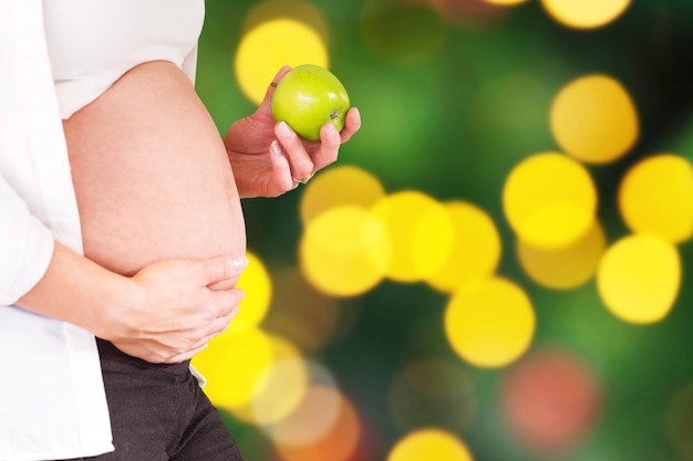 Samengestelde afbeelding van buik van zwangere vrouw met groene appel