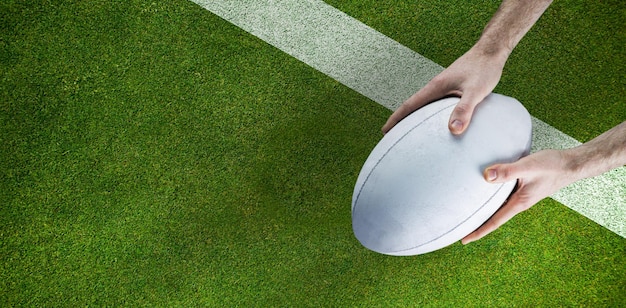 Samengestelde afbeelding van een rugbyspeler die een rugbybal poseert
