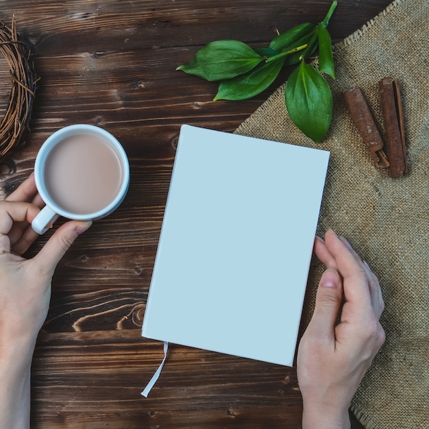 Samenstelling met boek, hand, kopje koffie en bladeren