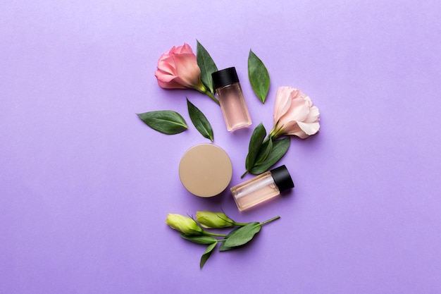 Samenstelling met cosmetische producten en mooie rozen op kleur achtergrond Flat lay